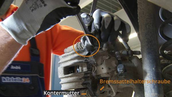 Der Bremssattel wird vom Bremssattelhalter getrennt. Bremssattel vom Halter abschrauben