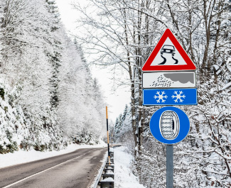 Hinweisschild: Schneekettenpflicht – Ketten müssen aufgezogen werden Verkehrsschild Schneekettenpflicht auf winterlicher Passstraße