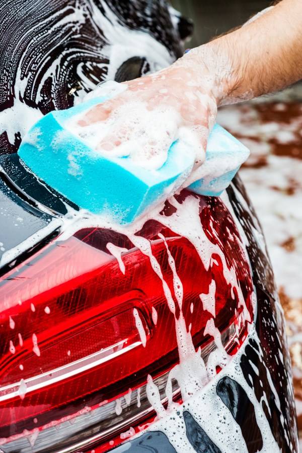 Bei der Zwei-Zonen-Technik wird das Auto von oben nach unten geputzt. Den Anfang macht die Vorreinigungung. Vorreinigen des Autos mit einem Schwamm